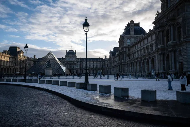 This photograph shows a general view of the Louvre Museum, with the Louvre pyramid (L) designed by Chinese-US architect Ieoh Ming Pei, after the first snowfall of the year in Paris on January 3, 2026. (Photo by Blanca CRUZ / AFP) 