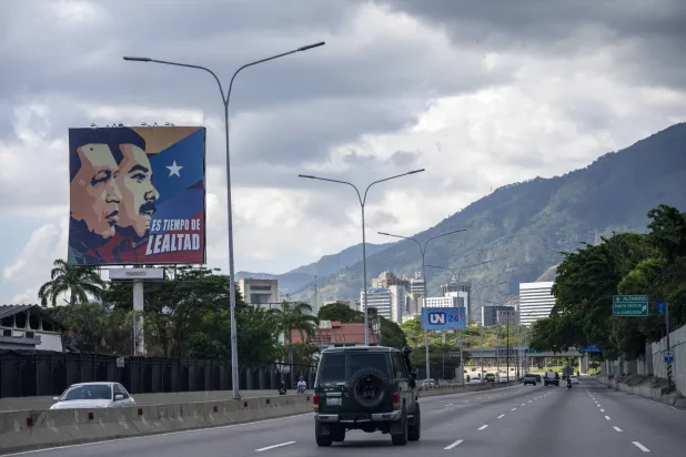 ملصق يحمل صورة الرئيسين الراحل هوغو تشافيز والحالي نيكولاس مادورو الذي اعتقلته الولايات المتحدة مع عبارة «حان وقت الحرية» (د.ب.أ)