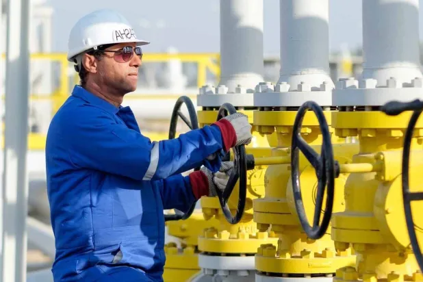 فني يدير صمام الفتح والإغلاق في منشأة للغاز تابعة لشركة «دانة غاز» الإماراتية (دانة غاز)