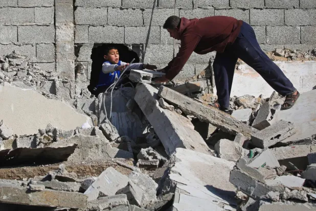 Filistinliler, dün Gazze'nin merkezindeki Megazi mülteci kampında İsrail tarafından yıkılan bir binanın enkazı arasında eşyalarını arıyor (AFP)