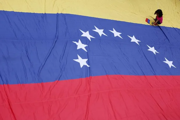 A young protester sits on a large-scale Venezuelan national flag during a protest following US military action in Venezuela, in Rio de Janeiro, Brazil, 05 January 2026. (EPA) 