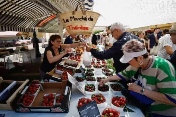 يتسوق المشترون الفواكه في سوق محلية بمدينة نيس في فرنسا (رويترز)