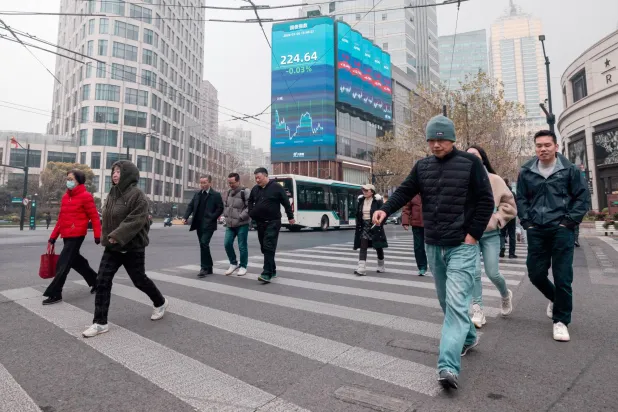 مشاة في أحد الشوارع بالضاحية المالية في مدينة شنغهاي (إ.ب.أ)