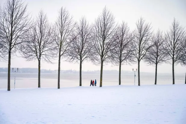  People walk along the Baltic Sea shore covered in a thick blanket of snow, in Stralsund, Germany, Tuesday, Jan. 6, 2026. (Stefan Sauer/dpa via AP) 