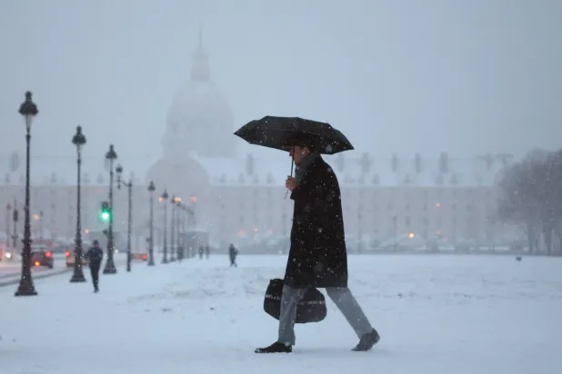 A man shelters from falling snow under an umbrella past as he walks on the snow-covered Esplanade des Invalides in Paris as winter weather with snow and cold temperatures hits a part of the country, France, January 7, 2026. (Reuters)