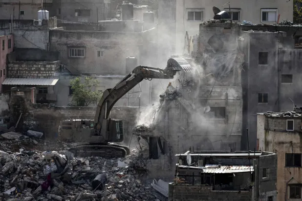 حفَّارة عسكرية إسرائيلية أثناء هدم أحد المباني السكنية في مخيم نور شمس بالضفة الغربية (أ.ف.ب)