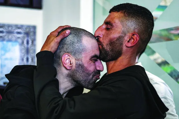 أسير فلسطيني محرَّر (يسار) يُقبِّله شقيقه لدى وصوله إلى رام الله قادماً من سجن عوفر الإسرائيلي (أ.ف.ب)