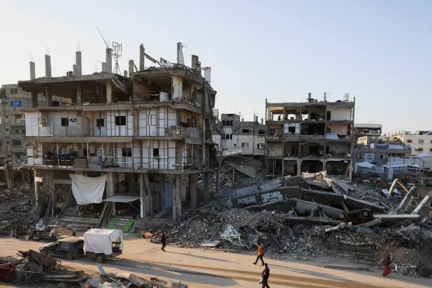 Palestinians walk past destroyed buildings in a neighborhood heavily damaged during the war, in Gaza City, January 5, 2026. (Reuters)