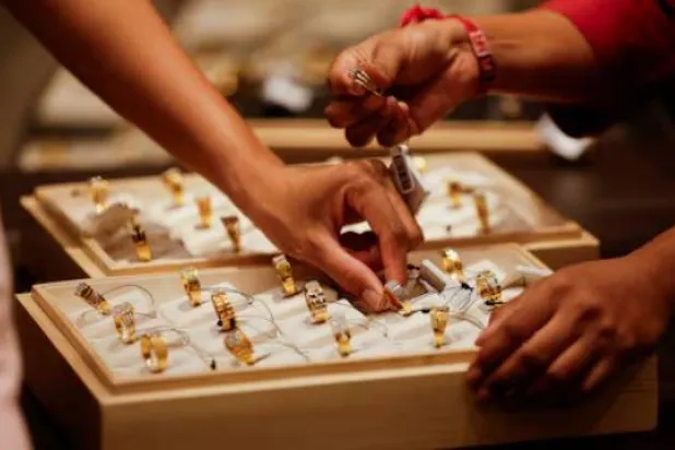 يعرض بائع خاتماً ذهبياً على زبائن داخل صالة عرض للمجوهرات في أحمد آباد بالهند (رويترز)