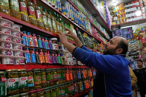 A shopkeeper arranges food oil bottles at his grocery store in northern Tehran, Iran, Tuesday, Jan. 6, 2026. (AP)