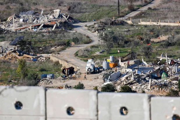 صورة مأخوذة من الجانب الإسرائيلي تظهر قوة من «اليونيفيل» بلبنان تقف مع جنود لبنانيين بجوار مبانٍ وسيارات دمَّرتها إسرائيل في قرية الضهيرة جنوب لبنان... 8 يناير (أ.ف.ب)