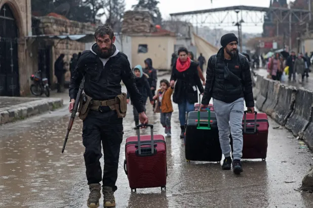 TOPSHOT - Residents of Aleppo's Sheikh Maqsud area evacuate their neighborhood after warnings from the Syrian army that called on civilians to get out of harms way, following the refusal of Kurdish fighter forces to leave Aleppo, on January 9, 2026. (Photo by OMAR HAJ KADOUR / AFP)