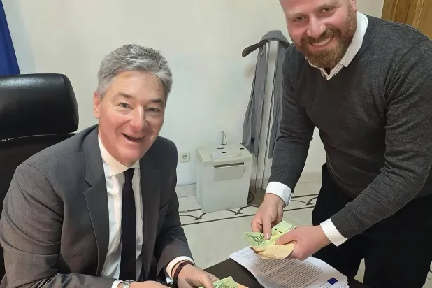 ميخائيل أونماخت القائم بأعمال بعثة الاتحاد الأوروبي في سوريا (يساراً) يمسك بأوراق العملة السورية الجديدة (حسابه عبر منصة «إكس»)