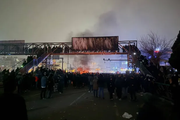 محتجون يحرقون لافتة معلقة فوق جسر للمشاة في حي بونك شمال غربي طهران الجمعة (تلغرام)