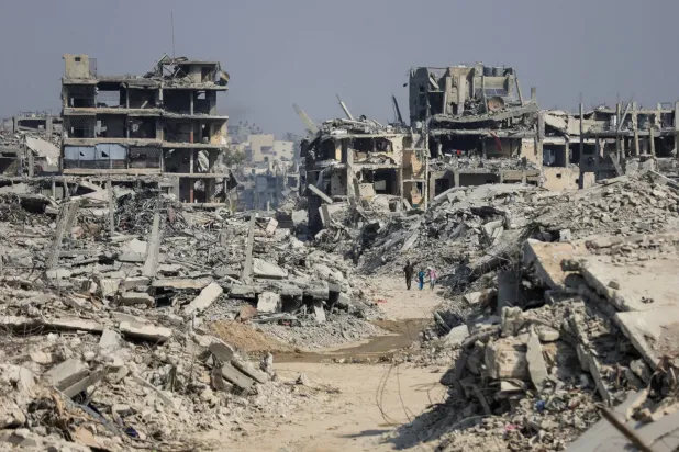 İsrail hava saldırıları sonucu yıkılan binaların arasında yürüyen Gazzeliler (Reuters)