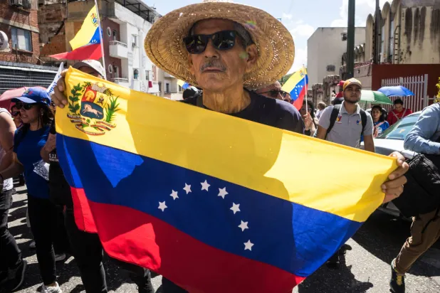 شخص يحمل العلم الفنزويلي خلال مظاهرة في كاراكاس (إ.ب.أ)