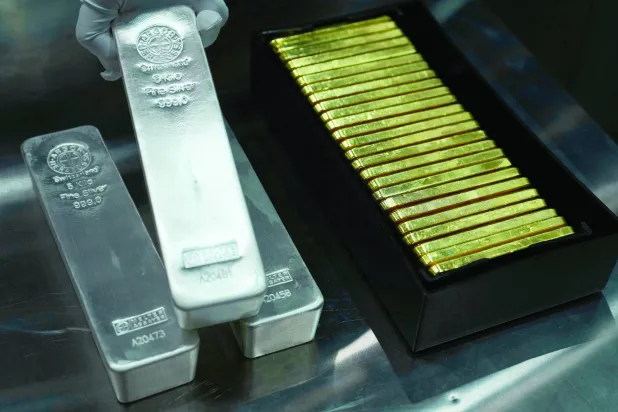 FILE - An employee of Pro Aurum gold house lifts 1 Kg silver bars of 999.9 purity besides 1 Kg gold bars in the safe deposit boxes room in Munich, Germany, Friday, April 25, 2025. (AP Photo/Matthias Schrader, File)