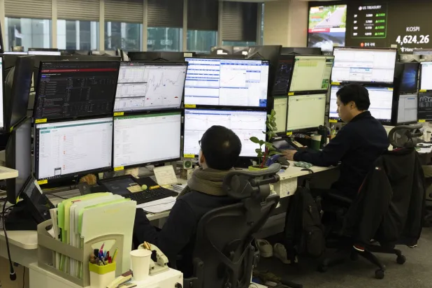 متداولون كوريون يتابعون أعمالهم أمام شاشات التداول ببنك «هانا» في سيول (إ.ب.أ)