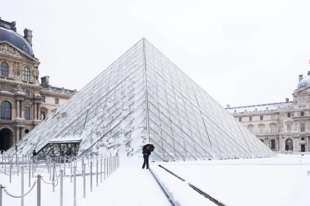 People walk next to the Louvre Museum covered in snow in Paris, France, 07 January 2026. (EPA)