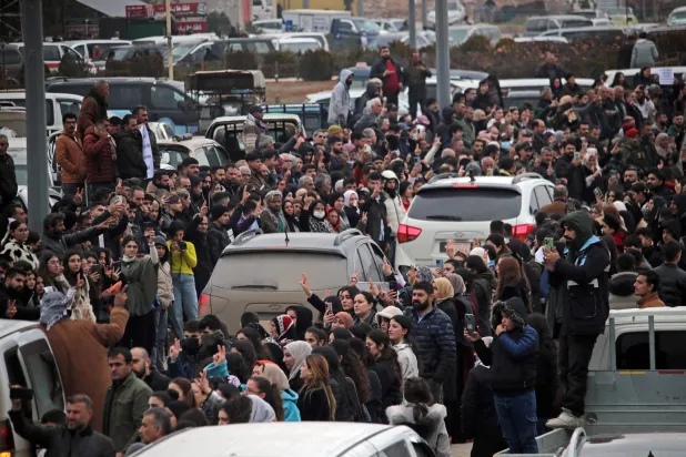 مواطنون تجمعوا حول مركبات تنقل مقاتلين أكراداً من مدينة حلب الشمالية أمس الأحد (أ.ف.ب)