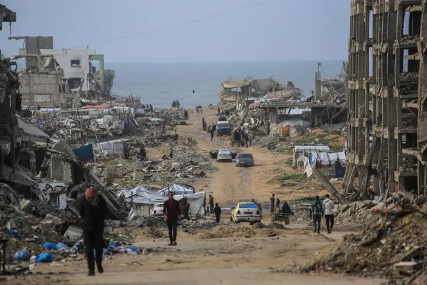 Palestinians walk along a road amid destroyed buildings in Jabalia, in the northern Gaza Strip, on January 10, 2026. (AFP)
