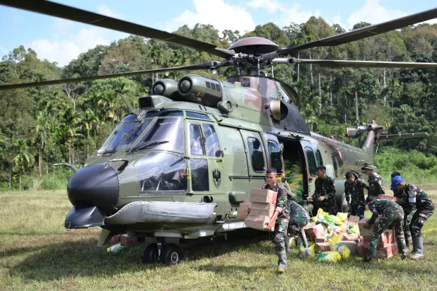 جنود من جيش إندونيسيا يفرغون مساعدات موجهة للمتضررين من فيضانات إقليم آتشيه تاميانغ كانت على متن مروحية عسكرية (أ.ب)