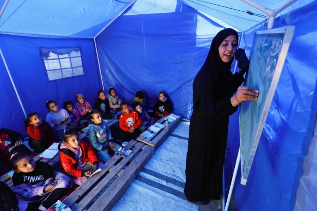 Yerinden edilmiş Filistinli çocuklar, Gazze'nin kuzeyindeki Beyt Lahiya'da, Hamas ve İsrail arasındaki sınır yakınlarında kurulan bir çadırda ders yapıyor (Reuters)
