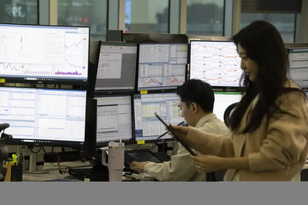 يعمل متداولون كوريون جنويون أمام شاشات عرض الأسهم في بنك هانا بسيول (إ.ب.أ)