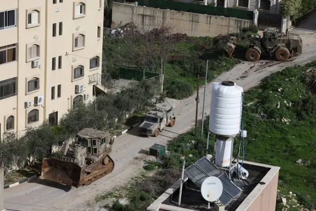 Israeli army bulldozers pass buildings during a military operation in Nur Shams refugee camp, near the West Bank city of Tulkarem, 12 January 2026. (EPA)