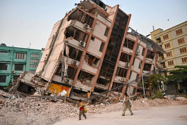 أطفال يمرون بجوار مبنى منهار في ماندالاي بعد 5 أيام من وقوع زلزال كبير ضرب وسط ميانمار (أ.ف.ب)
