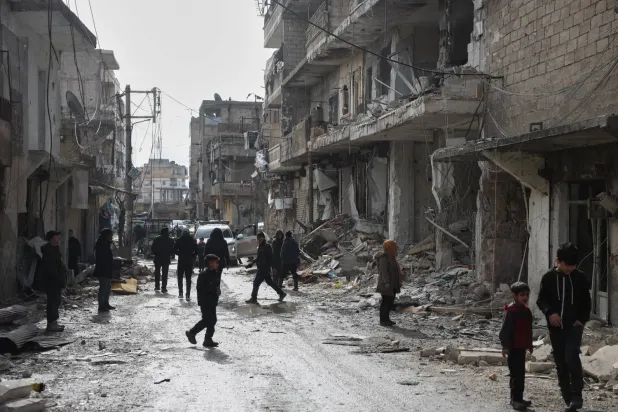 Suriye'de son çatışmaların ardından Halep'in Şeyh Maksud mahallesindeki binalarda meydana gelen hasarı inceleyen Suriyeliler (AP)