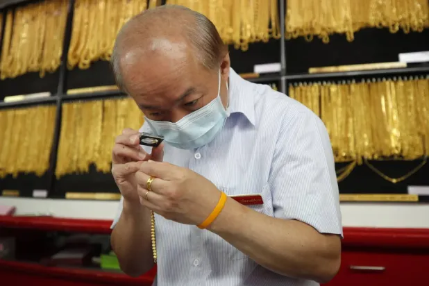  Bangkok'taki bir altın dükkanında altın takıları inceleyen bir kuyumcu (EPA)