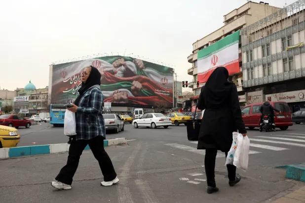 Iranians walk next to a billboard reading "Iran is our Homeland" at Enqelab Square in Tehran, Iran, 13 January 2026. (EPA)
