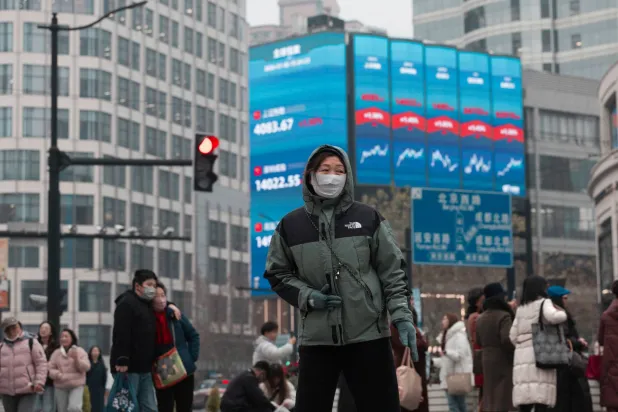 مشاة يمرون أمام شاشة عملاقة تعرض حركة الأسهم في مدينة شنغهاي الصينية (إ.ب.أ)