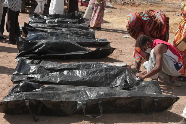 يتفقد أقارب ضحايا النزاع السوداني أسماءهم على أكياس الجثث بعد أن نقل الهلال الأحمر السوداني الرفات من مقابر مؤقتة إلى مقبرة محلية في الخرطوم (أ.ب)