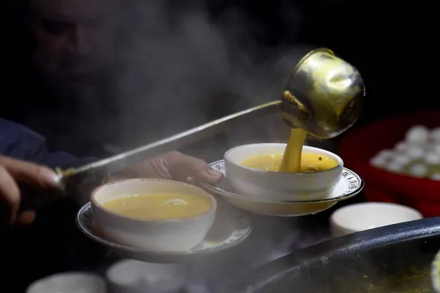 أشخاص يتناولون حساء الدجاج بمتجر على جانب الطريق في باكستان (إ.ب.أ)