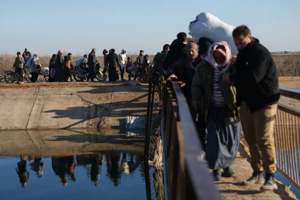 نازحون سوريون يسيرون لعبور معبر نهري بالقرب من قرية جريرة الإمام في ريف حلب الشرقي بالقرب من خط المواجهة بين القوات الحكومية و«قوات سوريا الديمقراطية» التي يقودها الأكراد في دير حافر 15 يناير 2026 (أ.ب)