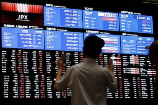 شخص يراقب لوحة أسعار الأسهم في بورصة طوكيو (رويترز)