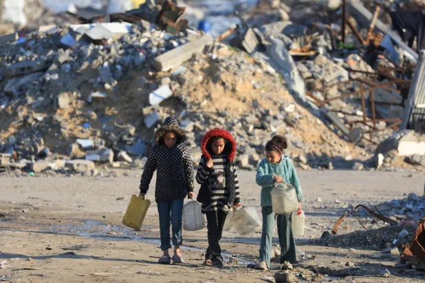 FILE PHOTO: Palestinian girls walk past the rubble of residential buildings destroyed during the war, in Gaza City, January 16, 2026. REUTERS/Dawoud Abu Alkas/File Photo