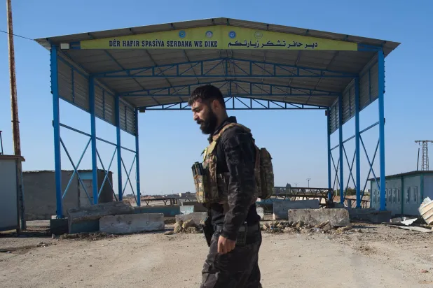 مقاتل من «قوات سوريا الديمقراطية» يظهر وسط نقطة تفتيش على طريق دير حفر - حلب (أ.ب)