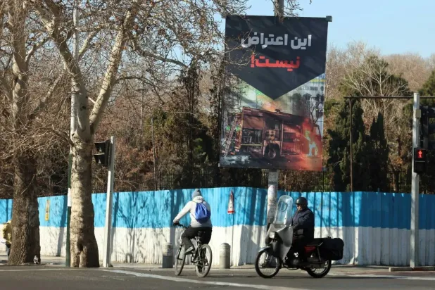 Iranians walk past a sign reading in Persian “This is not a protest” on a street in Tehran (EPA) 
