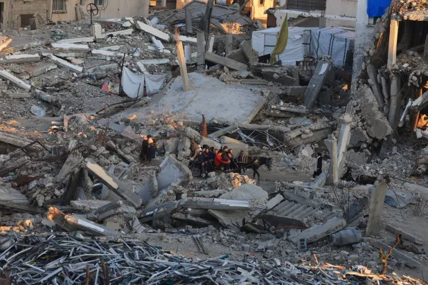Palestinians move past the rubble of residential buildings destroyed during the war, in Gaza City, January 16, 2026. REUTERS/Dawoud Abu Alkas