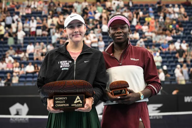 الروسية ميرا أندرييفا (يسار) تحتفل بكأس أديلايد إلى جوار الكندية فيكتوريا مبوكو (أ.ف.ب)