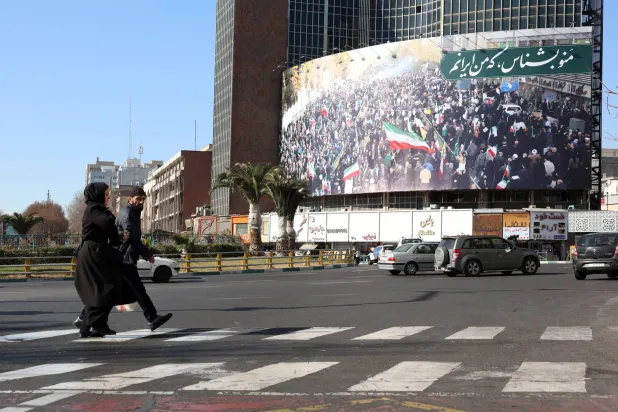 إيرانيون يسيرون في أحد شوارع طهران (إ.ب.أ)