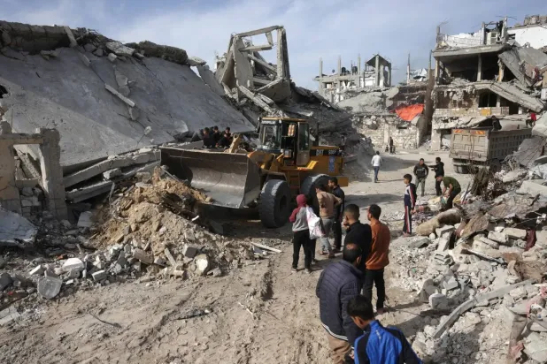 Gazze Şeridi'nin güneyindeki Han Yunus'ta yıkılmış binalar ve evlerden beton, metal ve moloz taşımak için kullanılan bir ekskavatör (AFP)