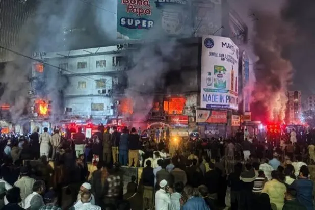 People gather as firefighters try to control a massive fire that broke out in a multi-story shopping mall, in Karachi, Pakistan, Sunday, Jan. 18, 2026. (AP Photo/Mohammad Farooq)