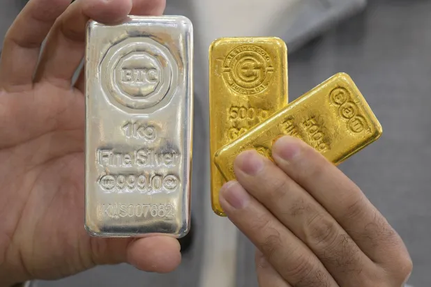 (FILES) A jeweler shows gold and silver bars at his shop in downtown Kuwait City on January 12, 2026. (Photo by YASSER AL-ZAYYAT / AFP)
