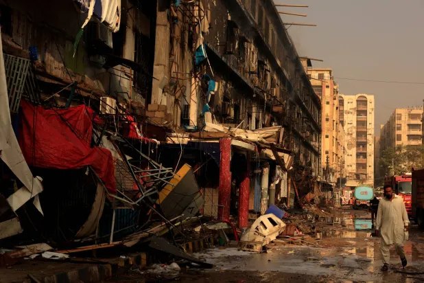 رجل يتجاوز الأنقاض عقب حريق هائل اندلع في مركز جول بلازا التجاري في كراتشي (رويترز)