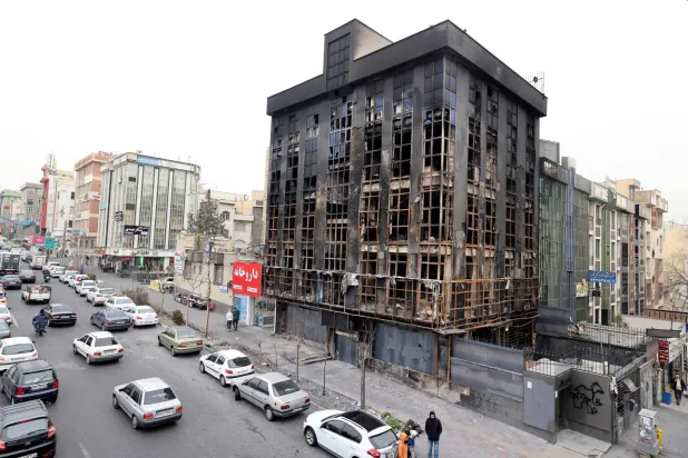 People walk past a burnt-out building destroyed during public protests in the Iranian capital Tehran on January 19, 26. (AFP)