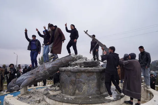 A group of civilians smash a statue of a Syrian Democratic Forces fighter in the city of Tabqa after the Syrian army took control of it, in Tabqa, Syria, January 18, 2026. REUTERS/Karam al-Masri TPX IMAGES OF THE DAY
